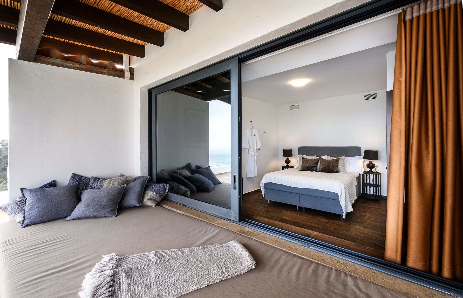A bedroom seen from the terrace, a daybed outside the sliding glass doors.