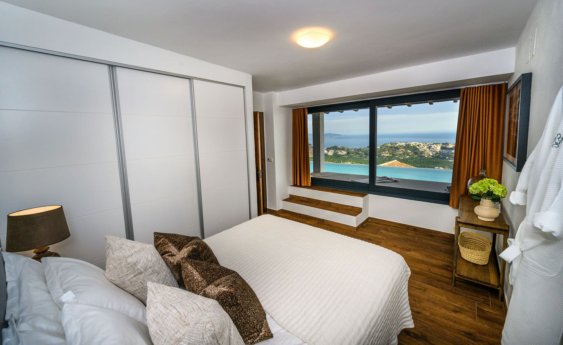A bedroom at El Cortijo, a wide window looking out over the pool and the coast.