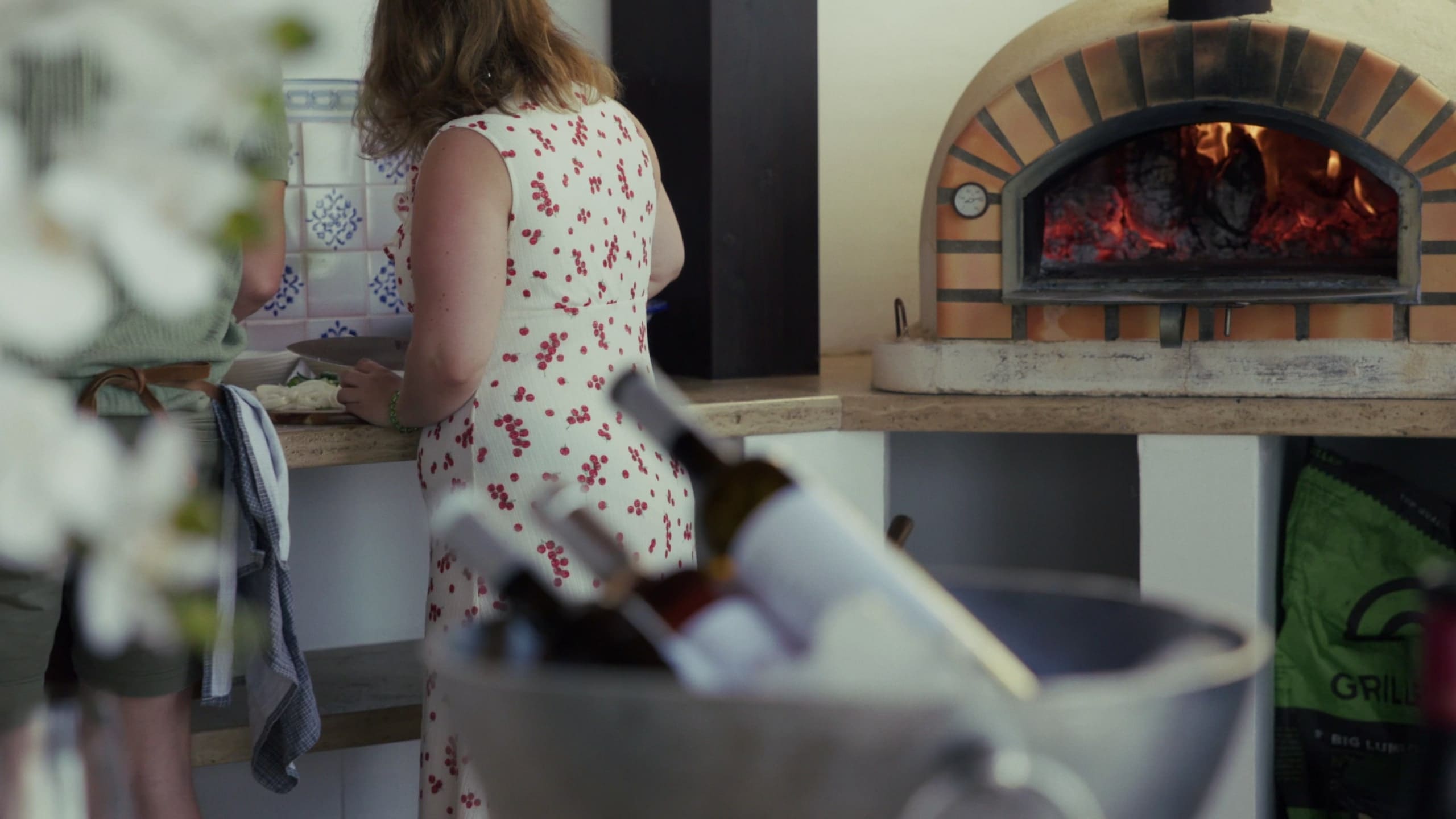 Cooking by the wood-fired oven in the outdoor kitchen, wine chilling in the foreground.