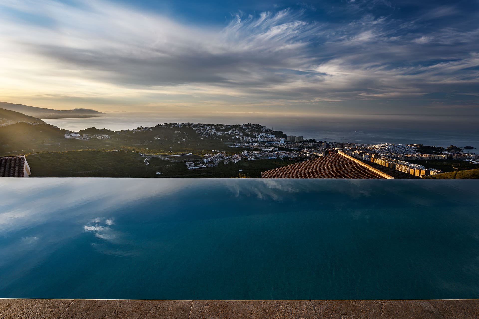 El Cortijo's infinity pool reflecting the clouds, Almuñécar and the coast beyond.