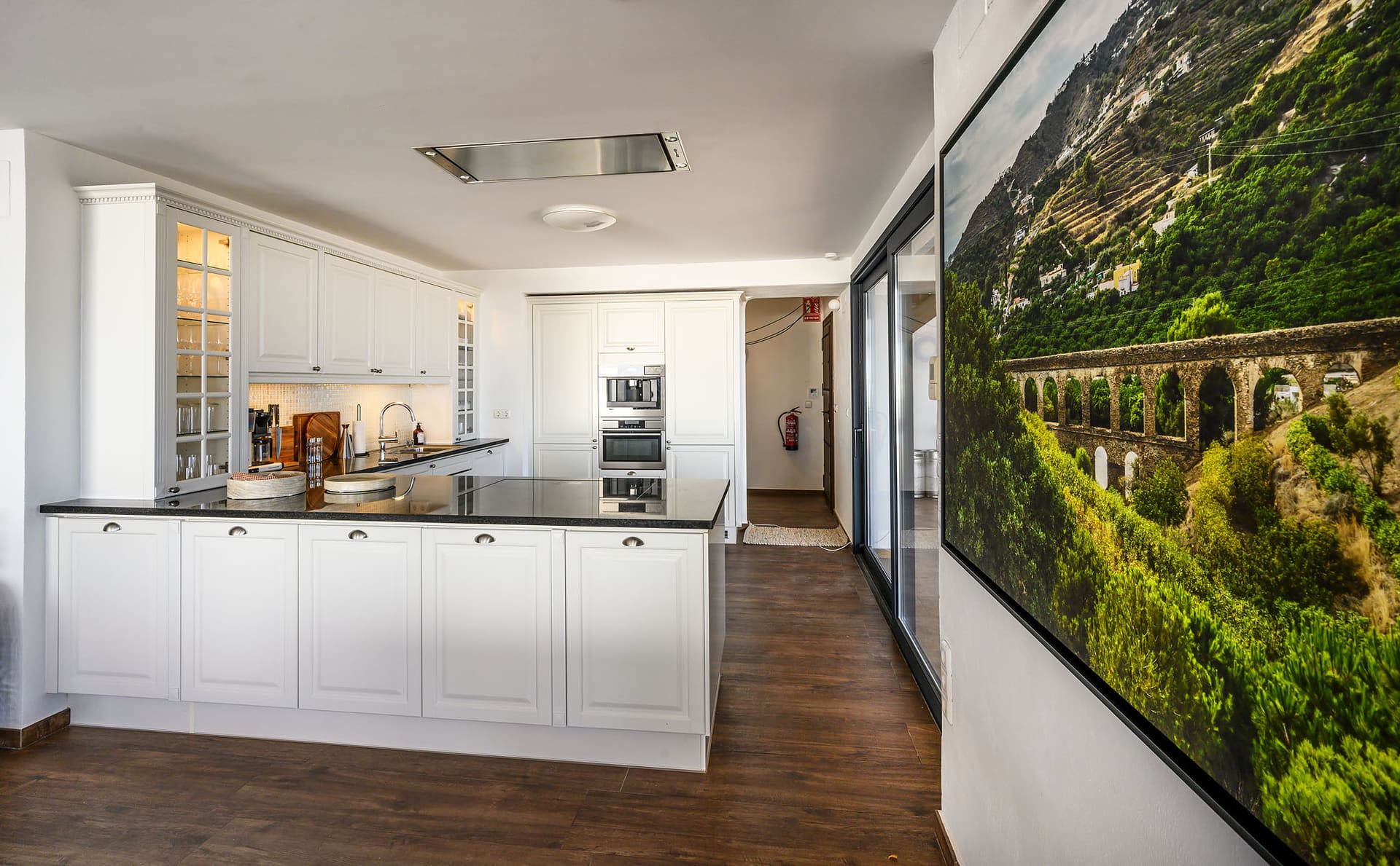 El Cortijo's white kitchen, an aqueduct photograph on the wall beside it.