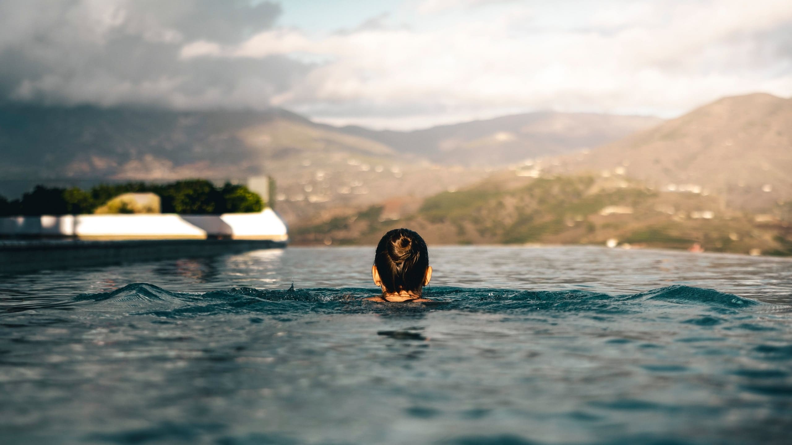 A swimmer in the infinity pool, looking out over the hills and the coast.