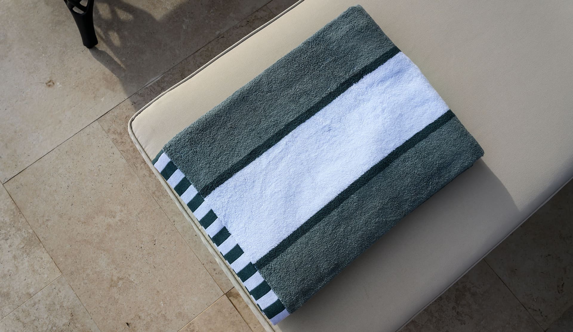 A striped pool towel folded on a lounger.