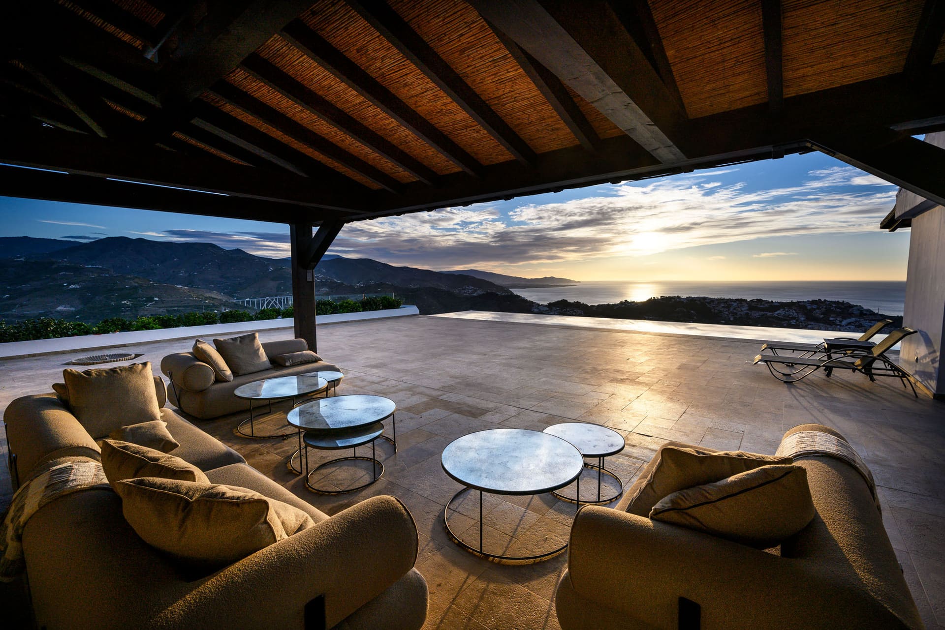 El Cortijo's covered terrace at sunset, low sofas facing the sea.