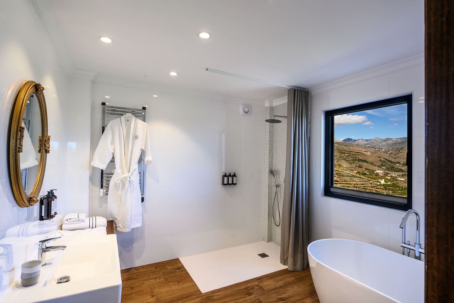 A bathroom with a freestanding bathtub and a window onto the mountains.