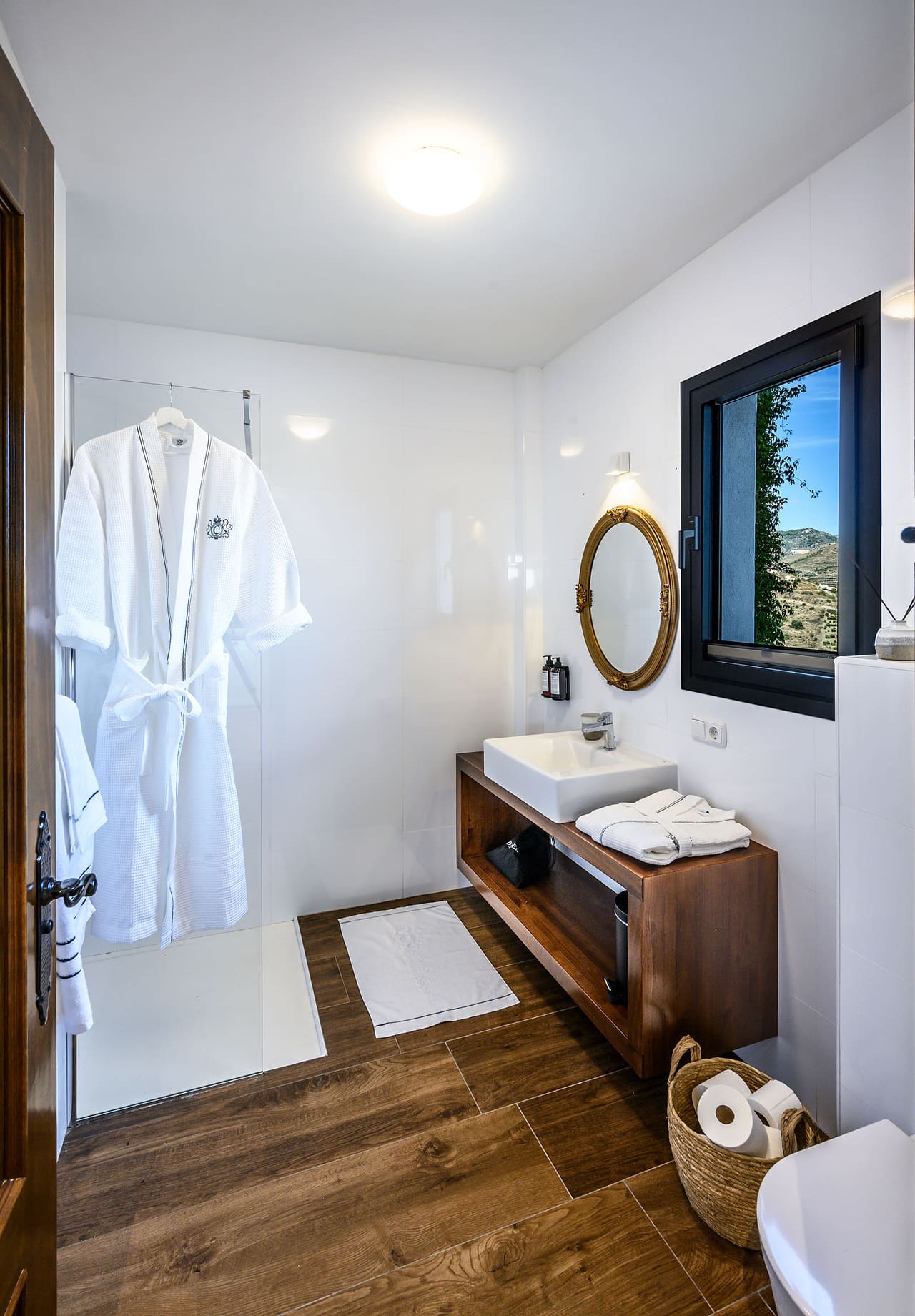 A bathrobe hanging by the washbasin, a round mirror beside it.