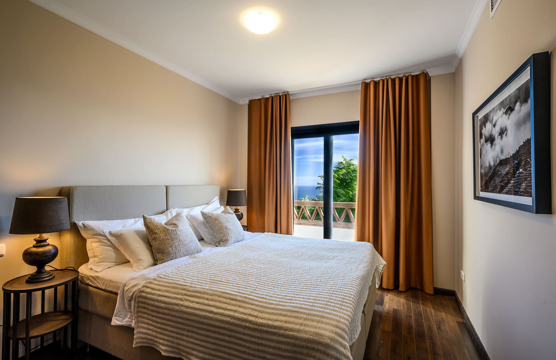 A bedroom at Villa Mango with long curtains and doors onto the view.
