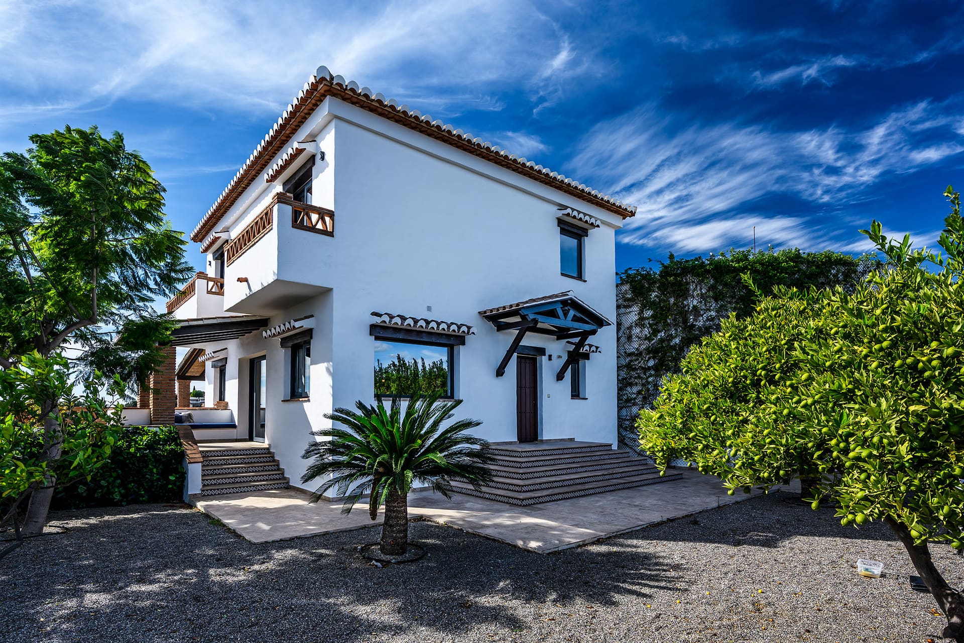 Villa Mango's whitewashed Andalusian front, a palm and orange trees before it.