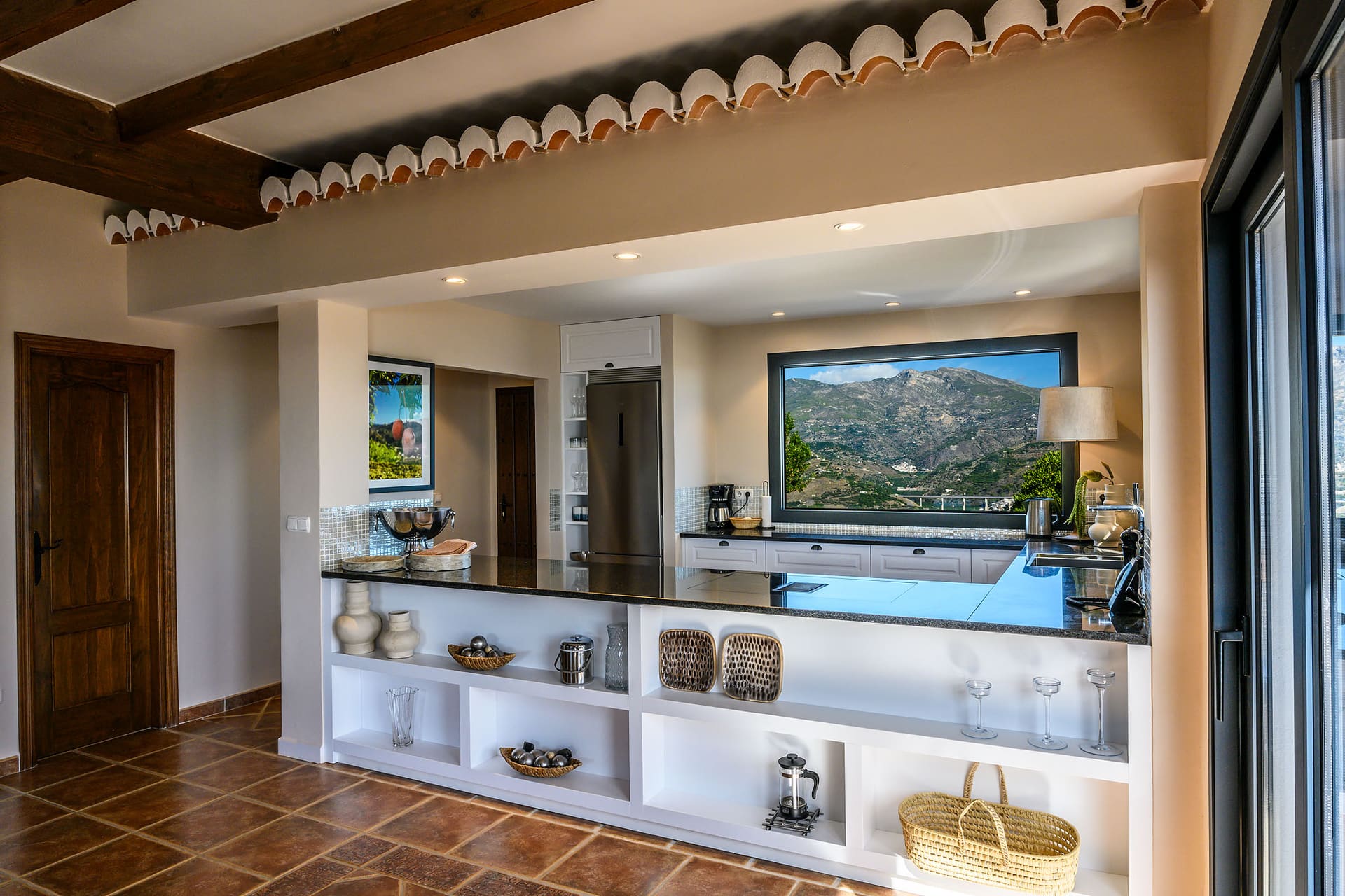 The kitchen counter at Villa Mango, open shelves below and the hills in the window.