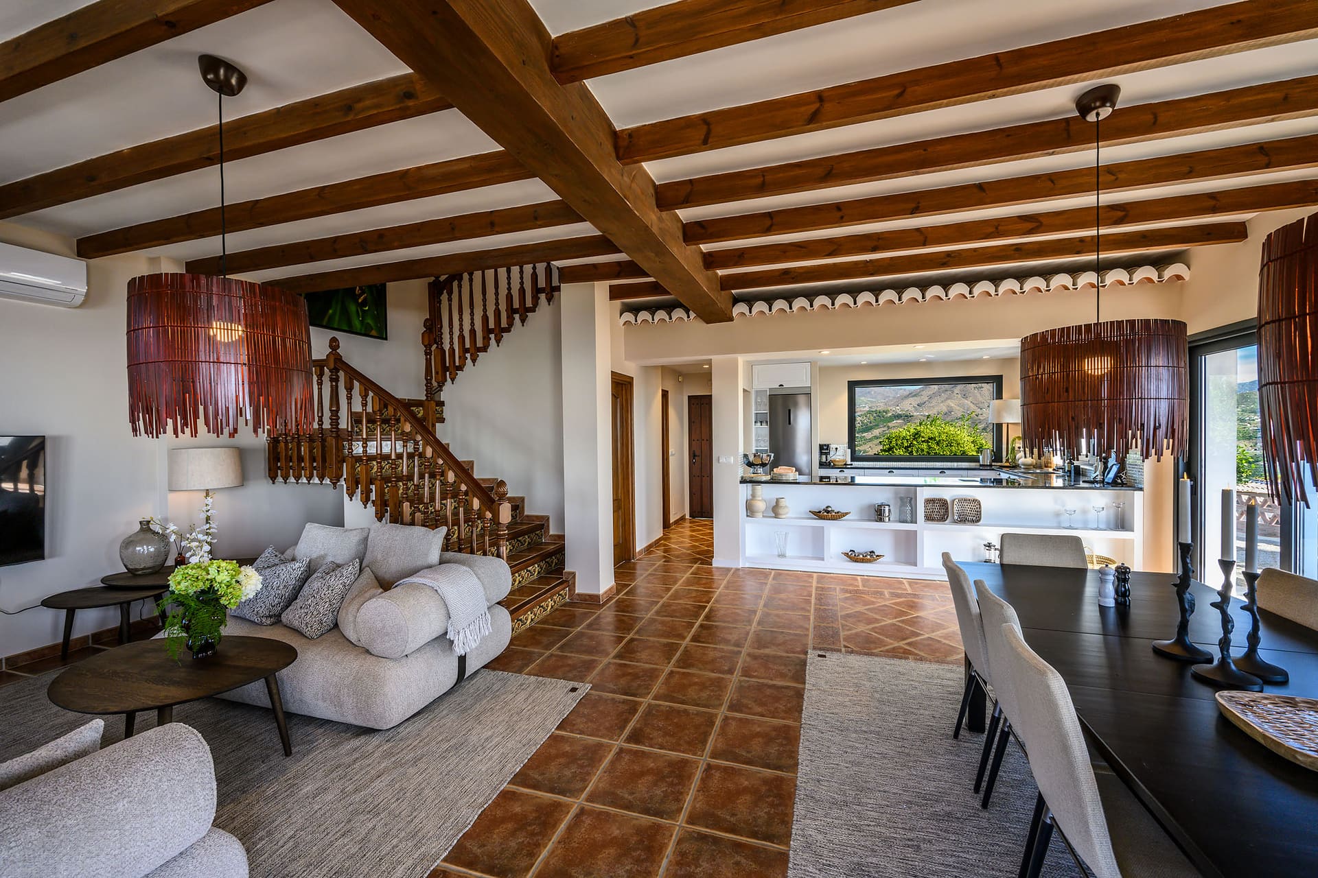 The open living and dining room at Villa Mango, beneath dark timber beams.