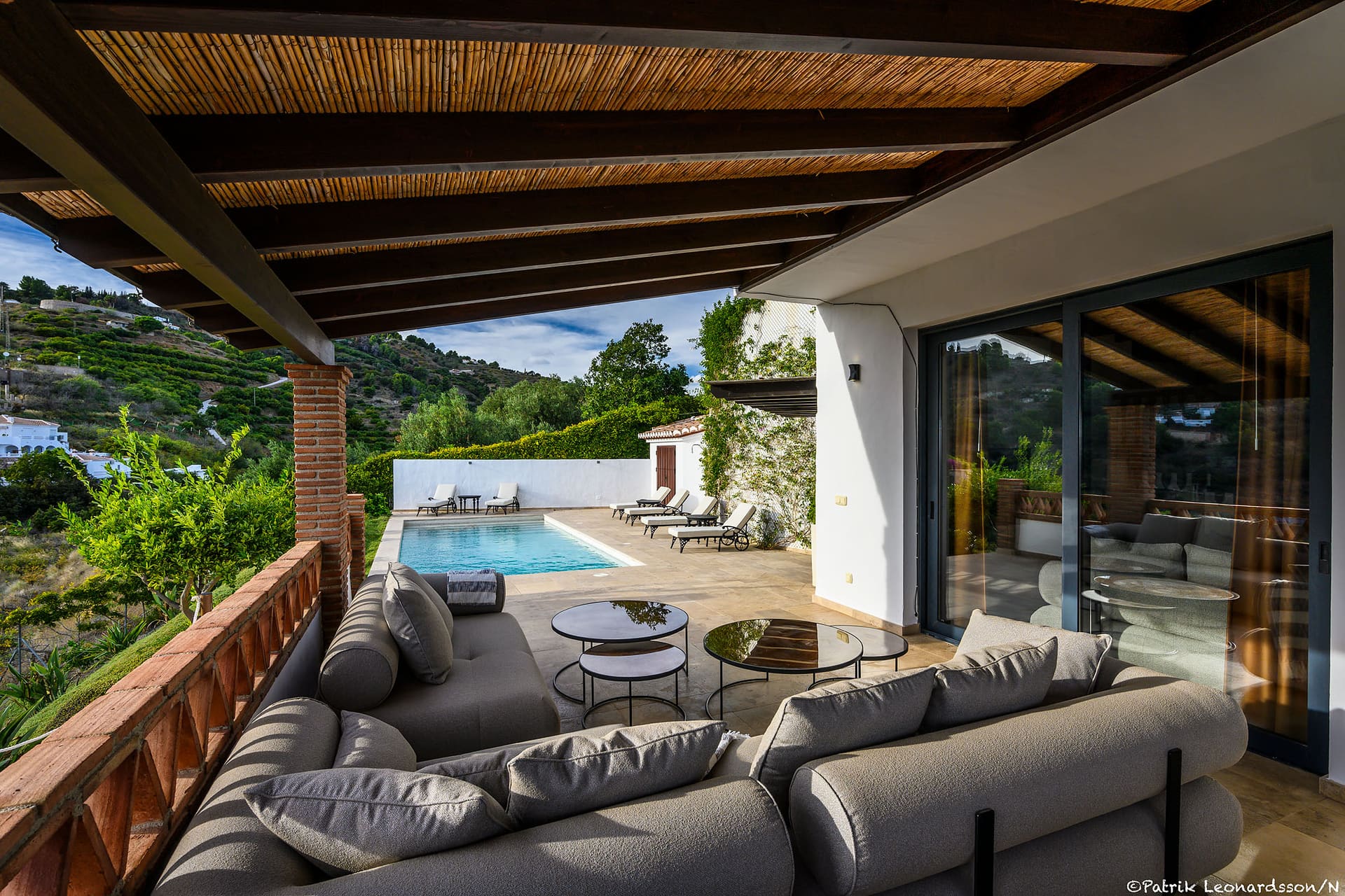 The shaded terrace lounge at Villa Mango, the pool below and the hills beyond.