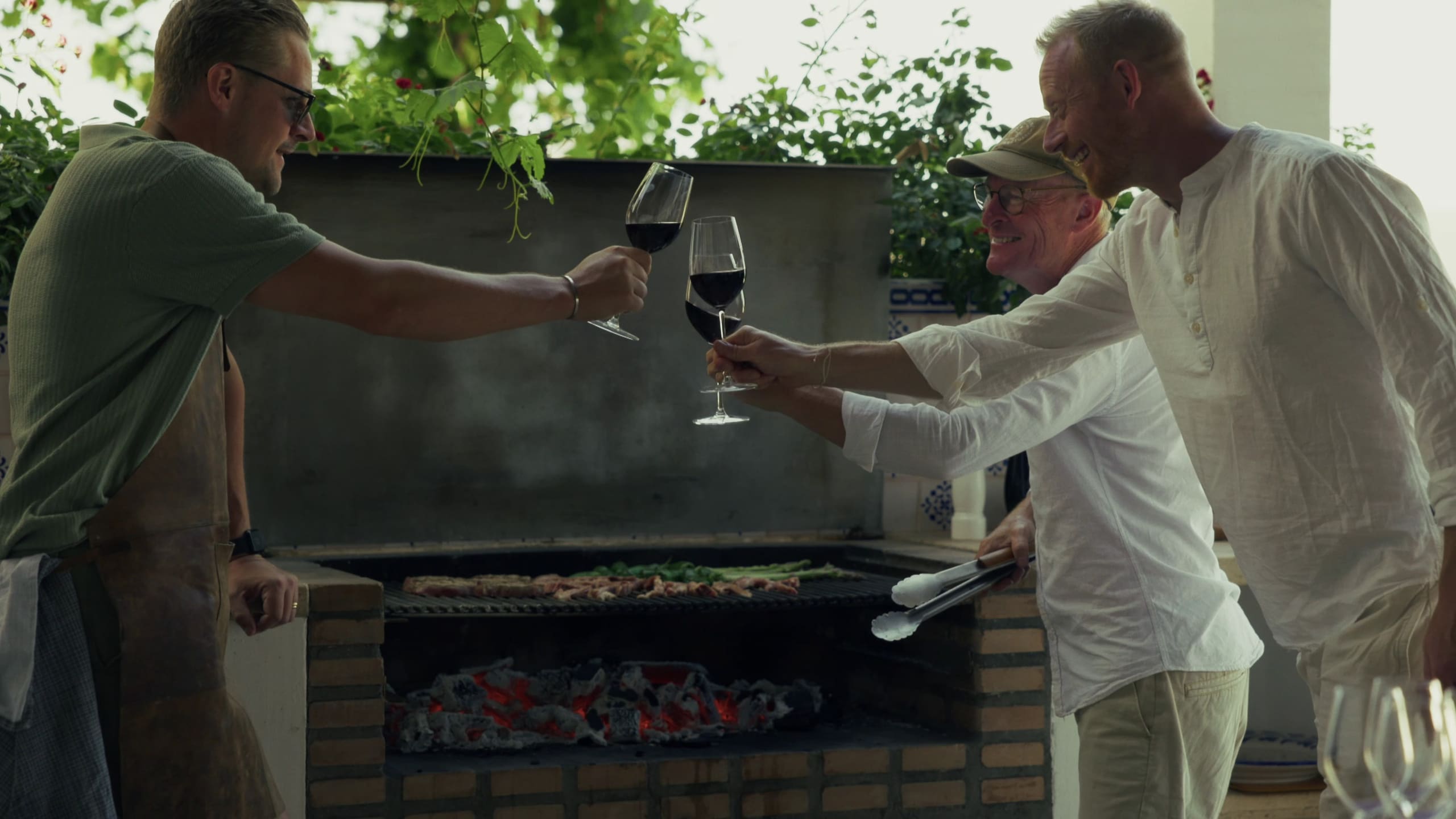 Guests toasting with red wine beside the barbecue.