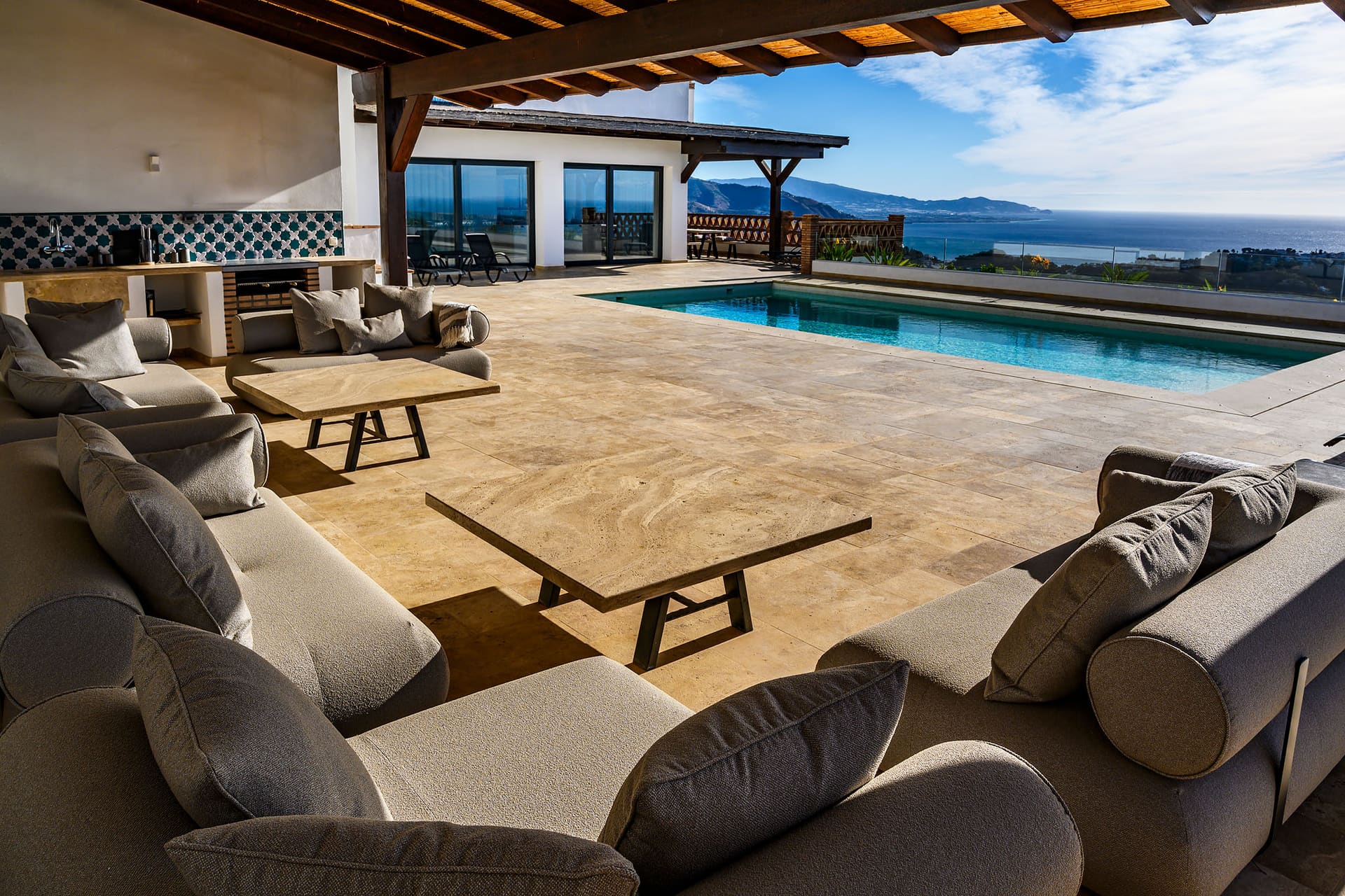 Beside the pool at Villa Naranja, sun loungers and the sea beyond.