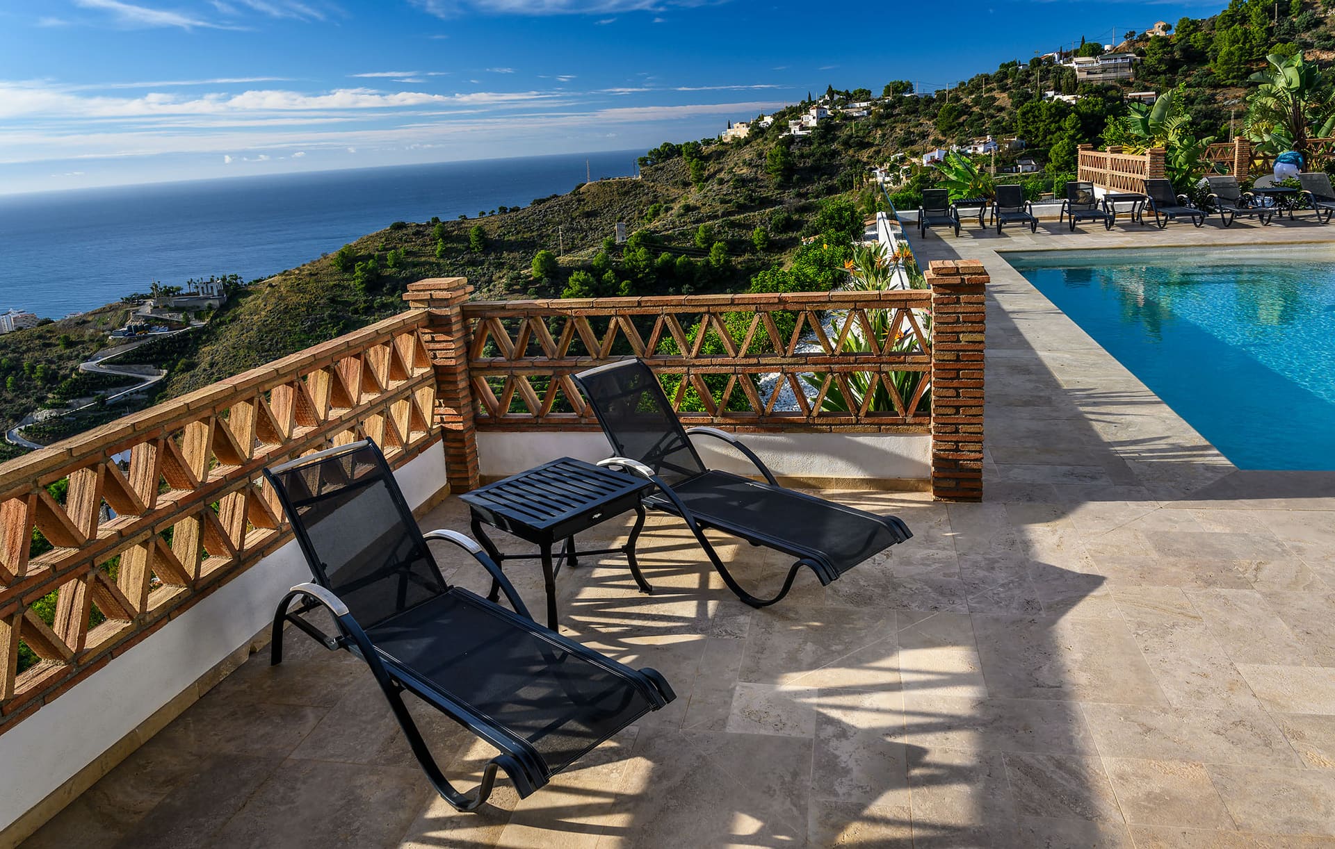 A sun chair beside the pool with the sea beyond.
