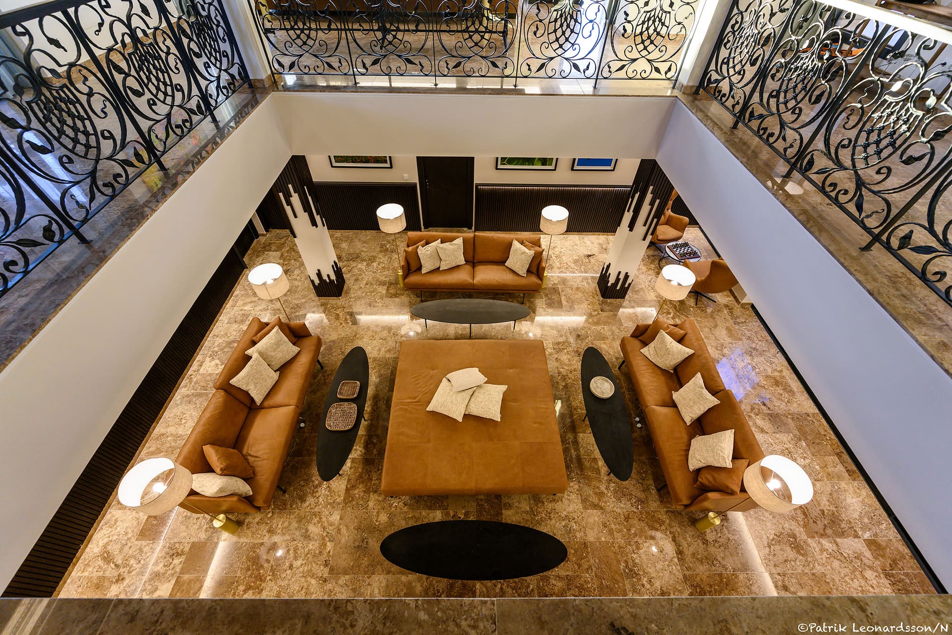 The atrium seen from the gallery, sofas arranged on the marble floor below.