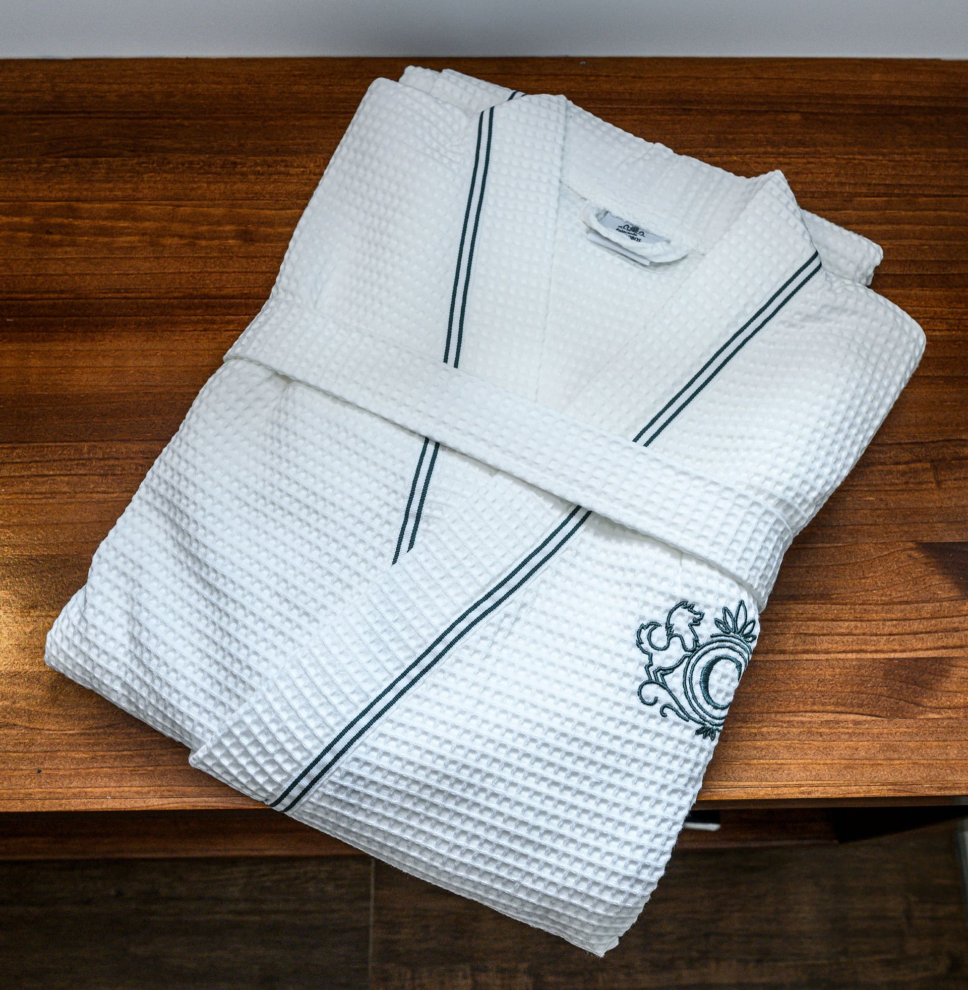 A folded white waffle bathrobe with the Cantalobos crest.