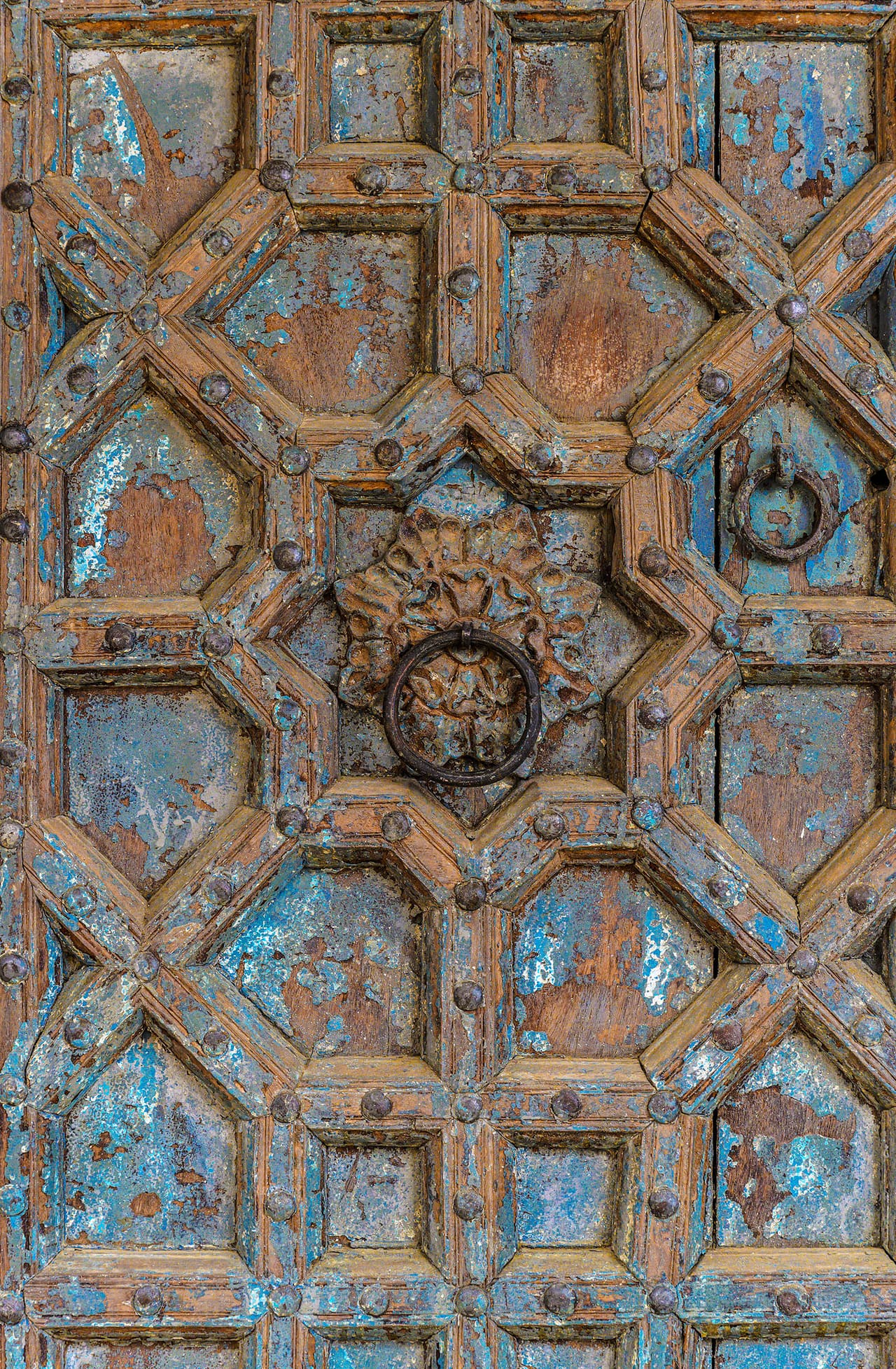 A carved wooden door, its old blue paint worn with age.