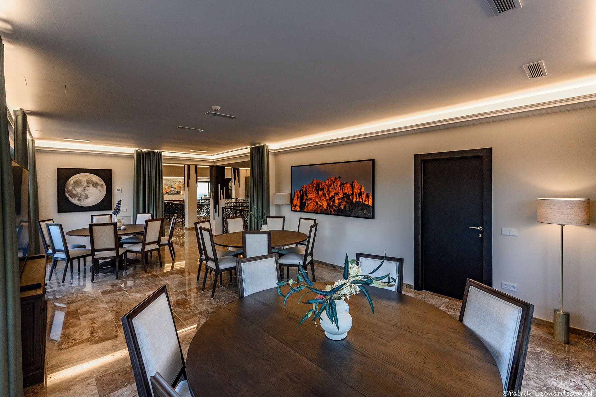 The meeting room, a round table and chairs beneath framed photographs.