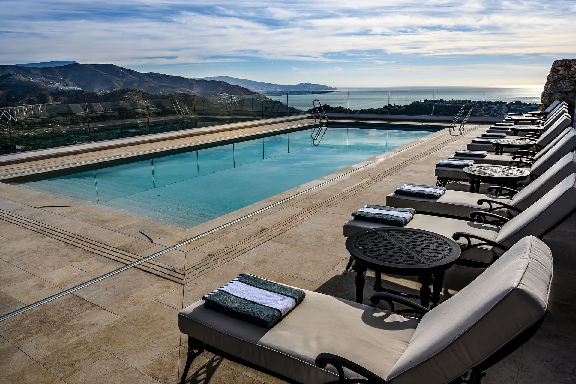 Loungers along the heated pool, the valley and the sea beyond.