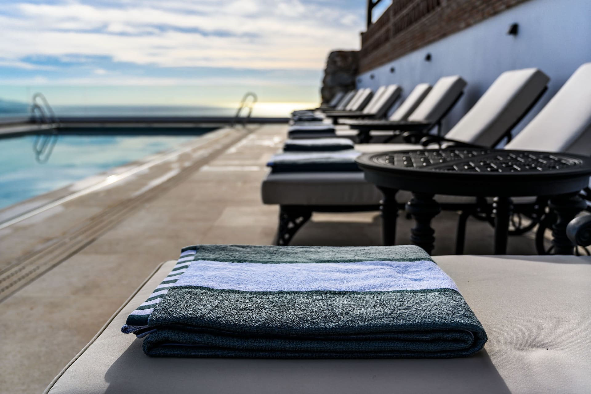 A folded towel on a lounger, the row of loungers running along the pool.