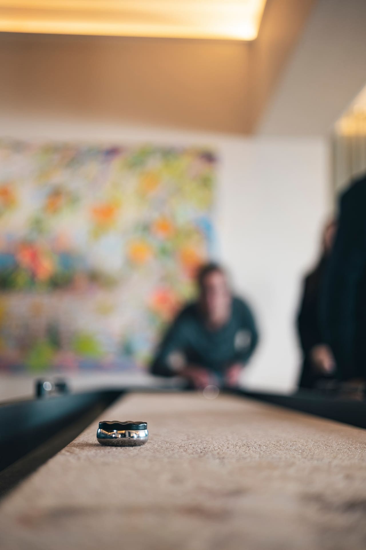 A game of shuffleboard, the puck sliding down the long wooden table.