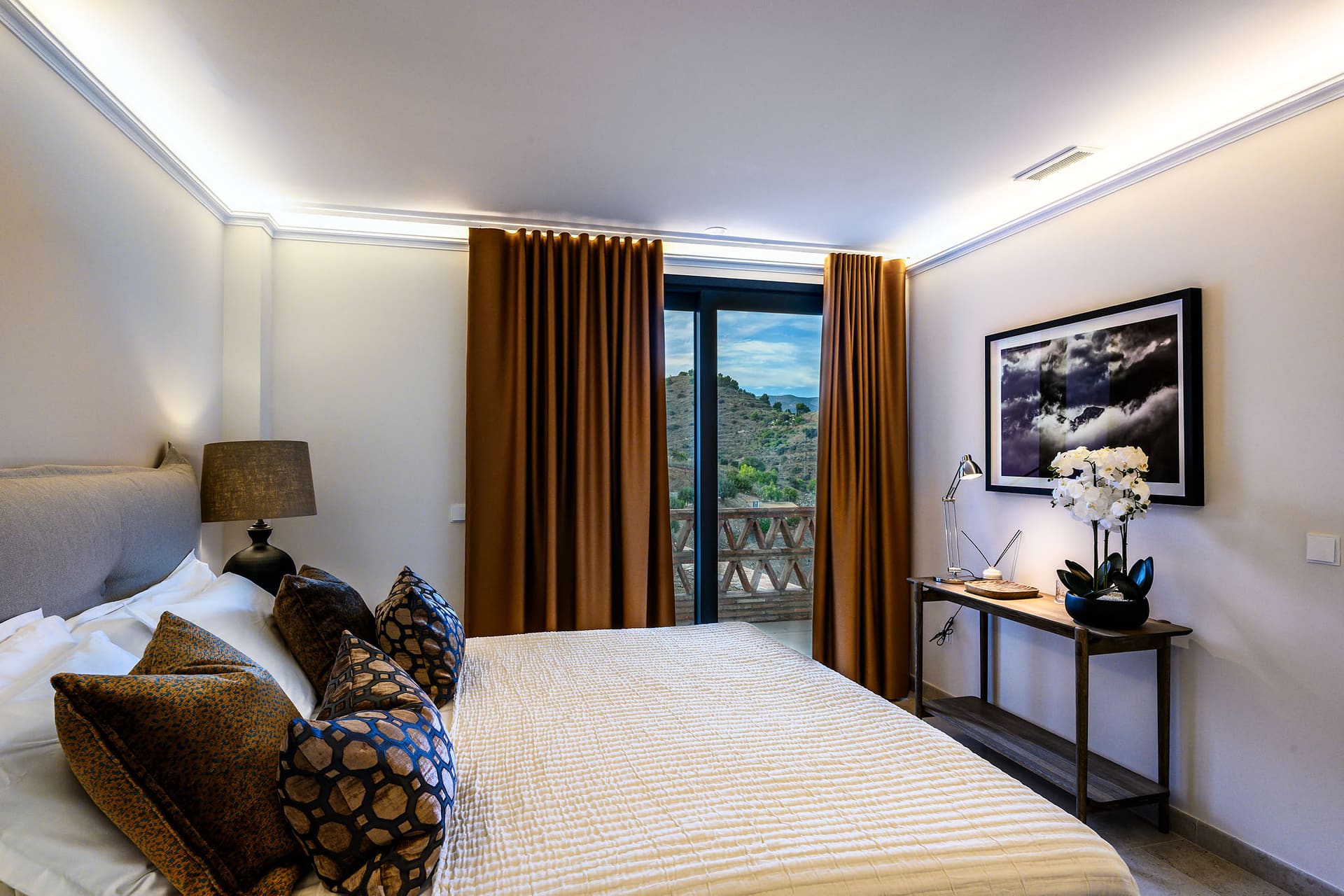 A suite bedroom with long amber curtains and doors onto the balcony.