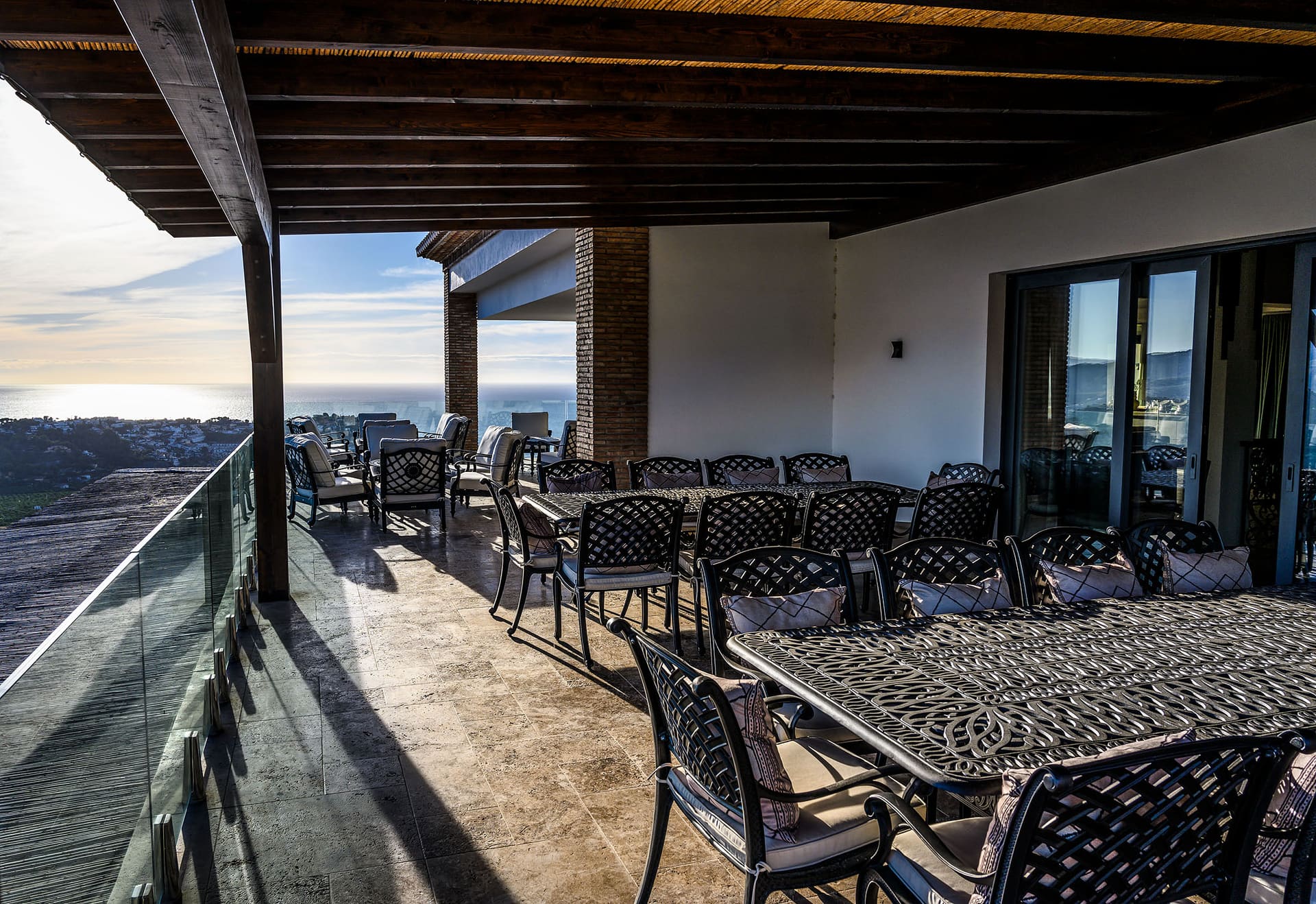 The covered terrace with a long wrought-iron table and the sea in the distance.